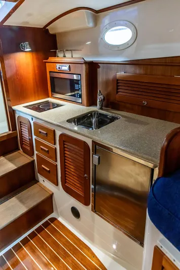 Valor Yacht Photos Pics 2014 Hinckley Talaria 34 yacht interior with kitchenette, wooden cabinetry, and stainless steel sink.