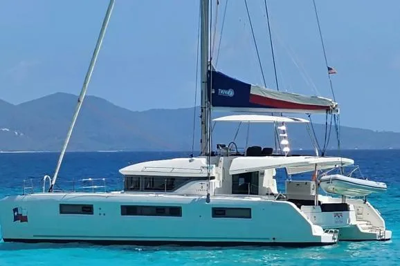 Lone Star Lagoon Yacht Photos Pics 2019 Lagoon 50 catamaran sailing on clear blue waters with scenic mountain backdrop.