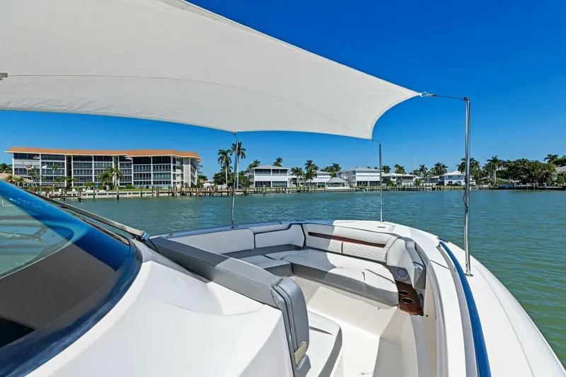 Luna B Yacht Photos Pics 2018 Tiara Yachts 38 LS on water, featuring spacious seating and sunshade, with waterfront buildings in view.