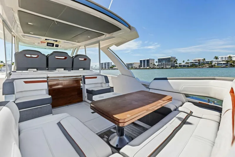 Luna B Yacht Photos Pics Luxurious 2018 Tiara Yachts 38 LS interior with seating and table, overlooking waterfront buildings.
