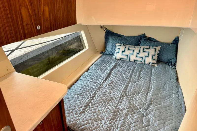  Yacht Photos Pics Cozy cabin interior of 2026 Intrepid 50 with blue bedding and large window.