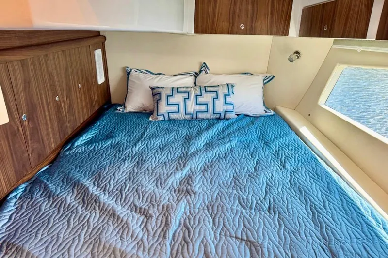  Yacht Photos Pics Cozy cabin interior of 2026 Intrepid 50 with blue bedding and wooden cabinets.