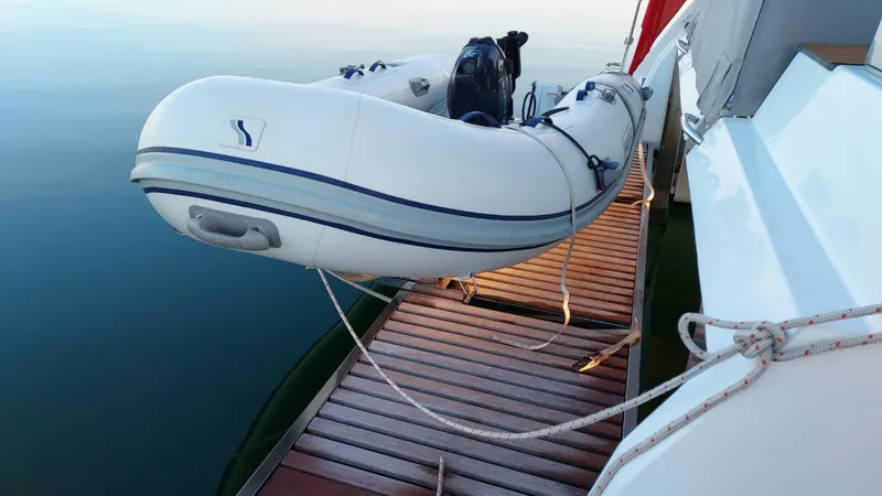 Super Trouper Yacht Photos Pics 2019 Fountaine Pajot Saona 47 with dinghy on wooden deck, calm water background.