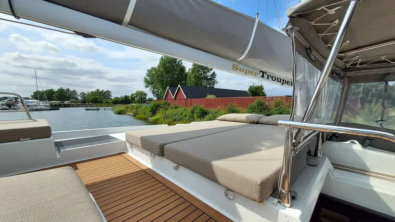 Super Trouper Yacht Photos Pics 2019 Fountaine Pajot Saona 47 catamaran with sunbathing area, docked near red buildings.