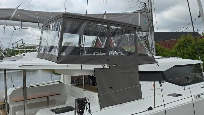 Super Trouper Yacht Photos Pics 2019 Fountaine Pajot Saona 47 catamaran with enclosed cockpit, docked by the water.