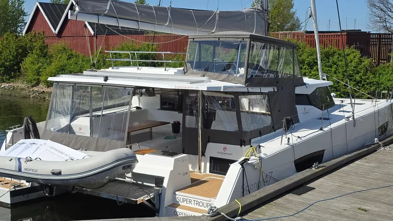 Super Trouper Yacht Photos Pics 2019 Fountaine Pajot Saona 47 catamaran docked, featuring spacious deck and dinghy.
