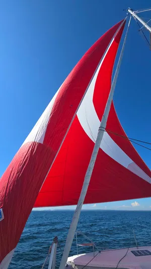Super Trouper Yacht Photos Pics Red sail on 2019 Fountaine Pajot Saona 47 catamaran against clear blue sky.