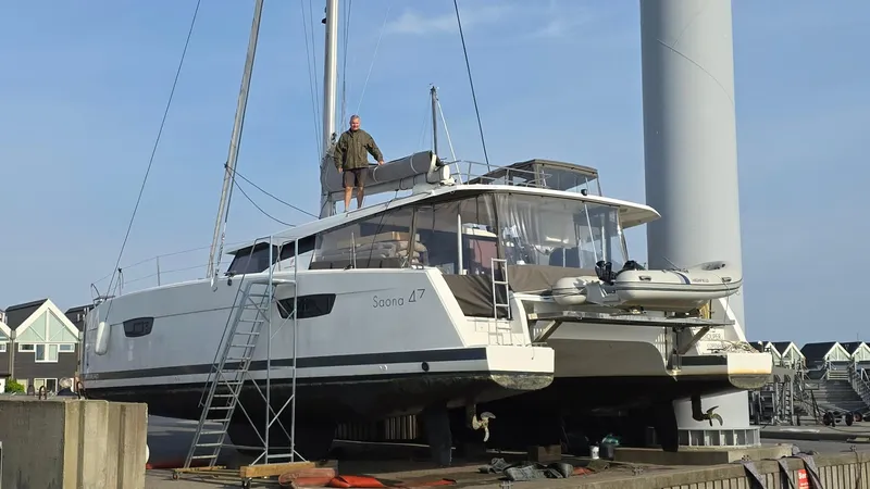 Super Trouper Yacht Photos Pics 2019 Fountaine Pajot Saona 47 catamaran on dry dock with a person standing on deck.