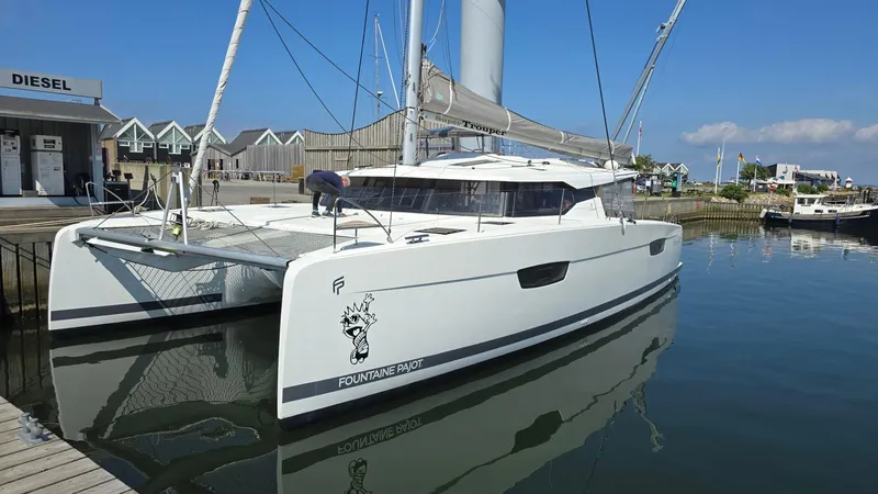 Super Trouper Yacht Photos Pics 2019 Fountaine Pajot Saona 47 catamaran docked at marina, clear sky, calm water.