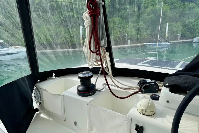 Promprang Yacht Photos Pics Cockpit view of 2020 Lagoon 50 yacht with ropes and winch, docked near lush greenery.