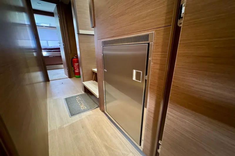 Promprang Yacht Photos Pics Interior hallway of 2020 Lagoon 50 yacht with wooden paneling and stainless steel door.