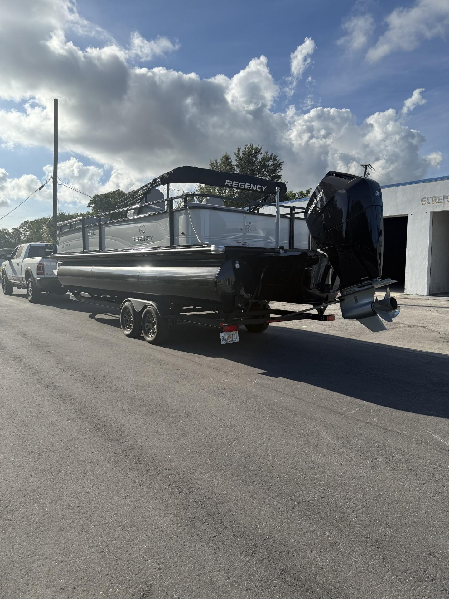 2024 Regency 250 DL3 pontoon boat on trailer, parked on sunny street.