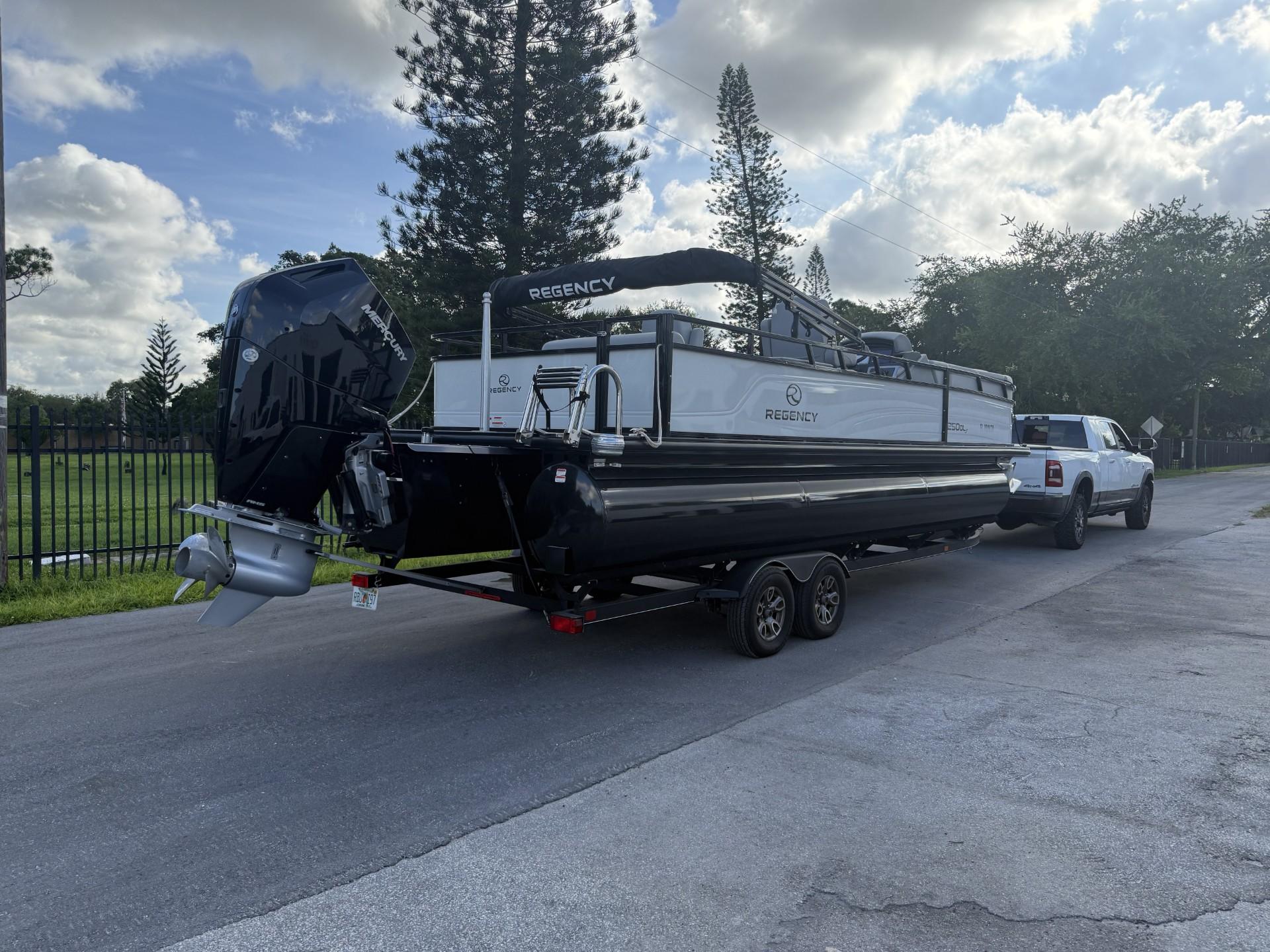 2024 Regency 250 DL3 pontoon boat on trailer, parked on a sunny street.