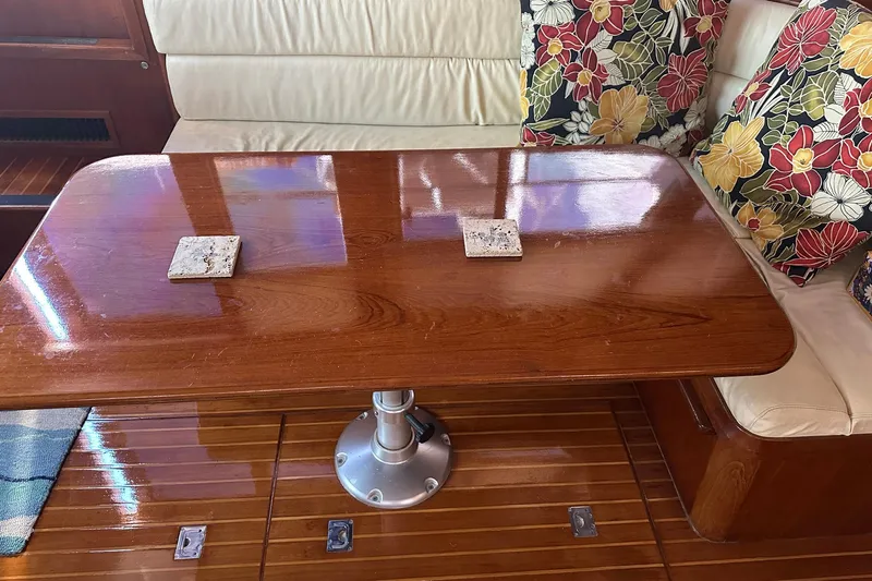 Off Ramp Yacht Photos Pics Wooden table with floral cushions in a 2002 Novatec Sundeck yacht interior.