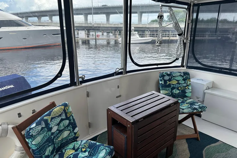 Off Ramp Yacht Photos Pics 2002 Novatec Sundeck interior with fish-patterned chairs and wooden table, overlooking marina.