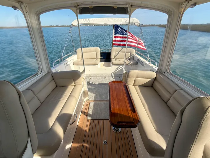 Wild Rose Yacht Photos Pics 2015 MJM 36z Downeast boat interior with American flag, spacious seating, and wooden table.