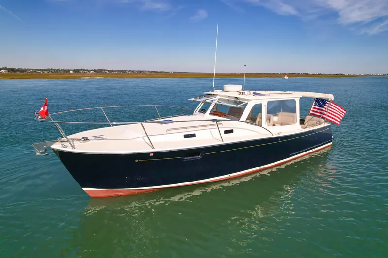 Wild Rose Yacht Photos Pics 2015 MJM 36z Downeast boat on calm water, featuring flags and sleek design.
