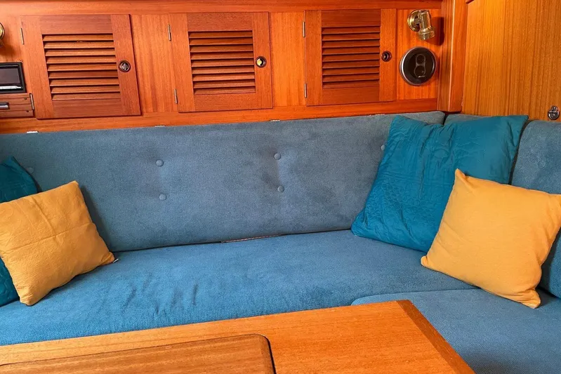  Yacht Photos Pics Cozy interior of 1990 Hallberg-Rassy 36 yacht with blue sofa and colorful cushions.