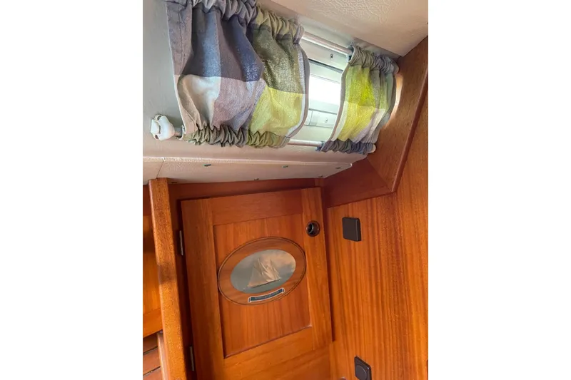  Yacht Photos Pics Interior of 1990 Hallberg-Rassy 36 yacht with wooden door and colorful curtain.