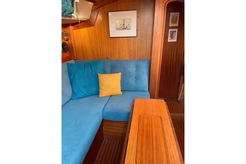 Yacht Photos Pics Cozy interior of 1990 Hallberg-Rassy 36 sailboat with blue seating and wooden accents.