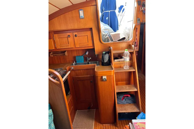  Yacht Photos Pics Interior of 1990 Hallberg-Rassy 36 sailboat with wooden cabinetry and compact kitchen area.