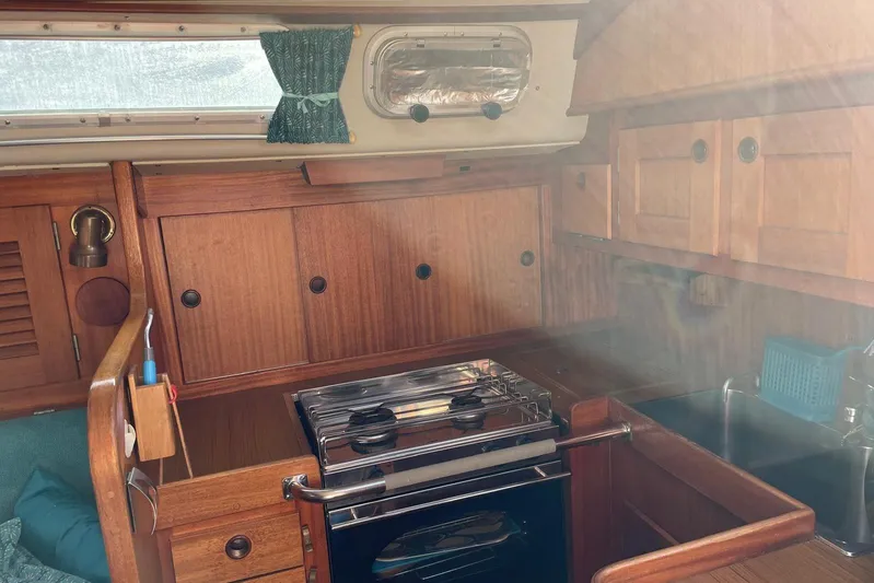 Yacht Photos Pics Interior of 1990 Hallberg-Rassy 36 sailboat, featuring a wooden kitchen with stove and sink.