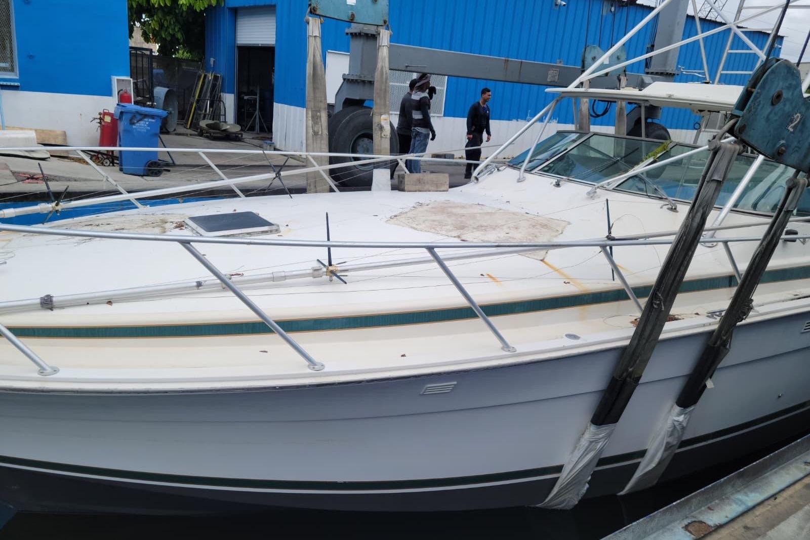 1995 Bertram 46 Moppie boat docked at a marina with blue buildings.