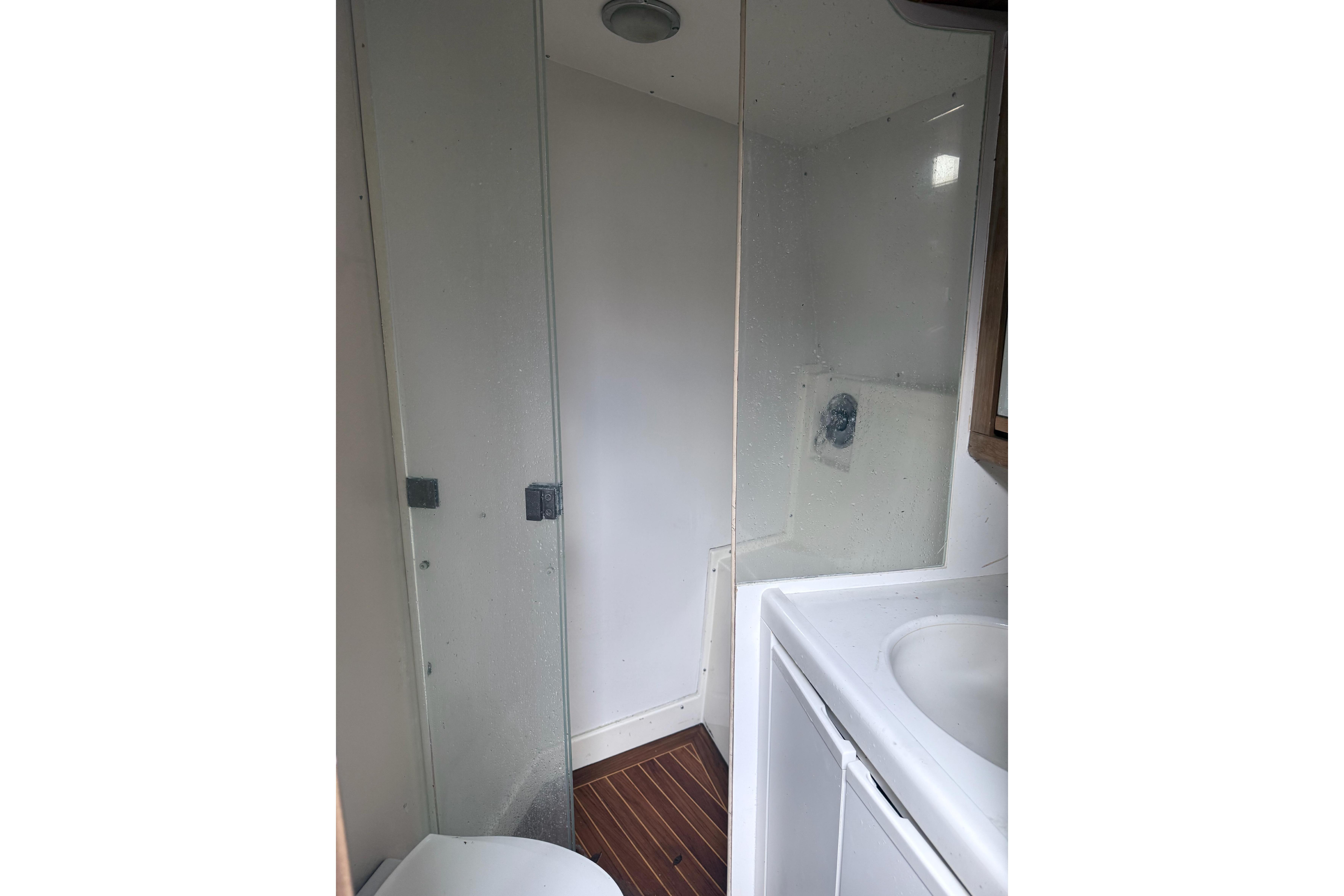 Bathroom interior of 1995 Bertram 46 Moppie yacht with shower and sink.