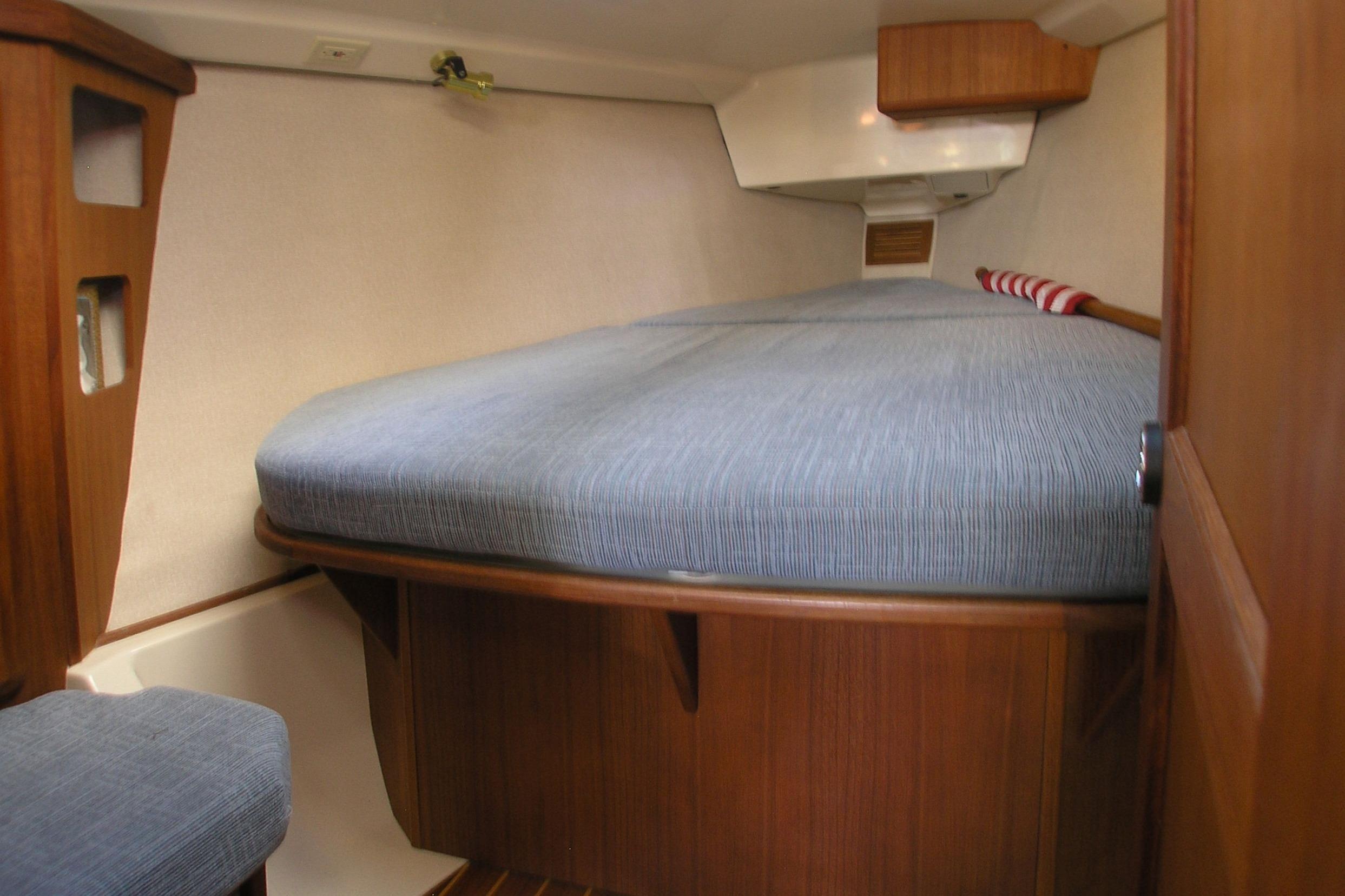 Interior cabin of 1996 Hunter 37.5 Legend sailboat with blue bedding and wooden finish.