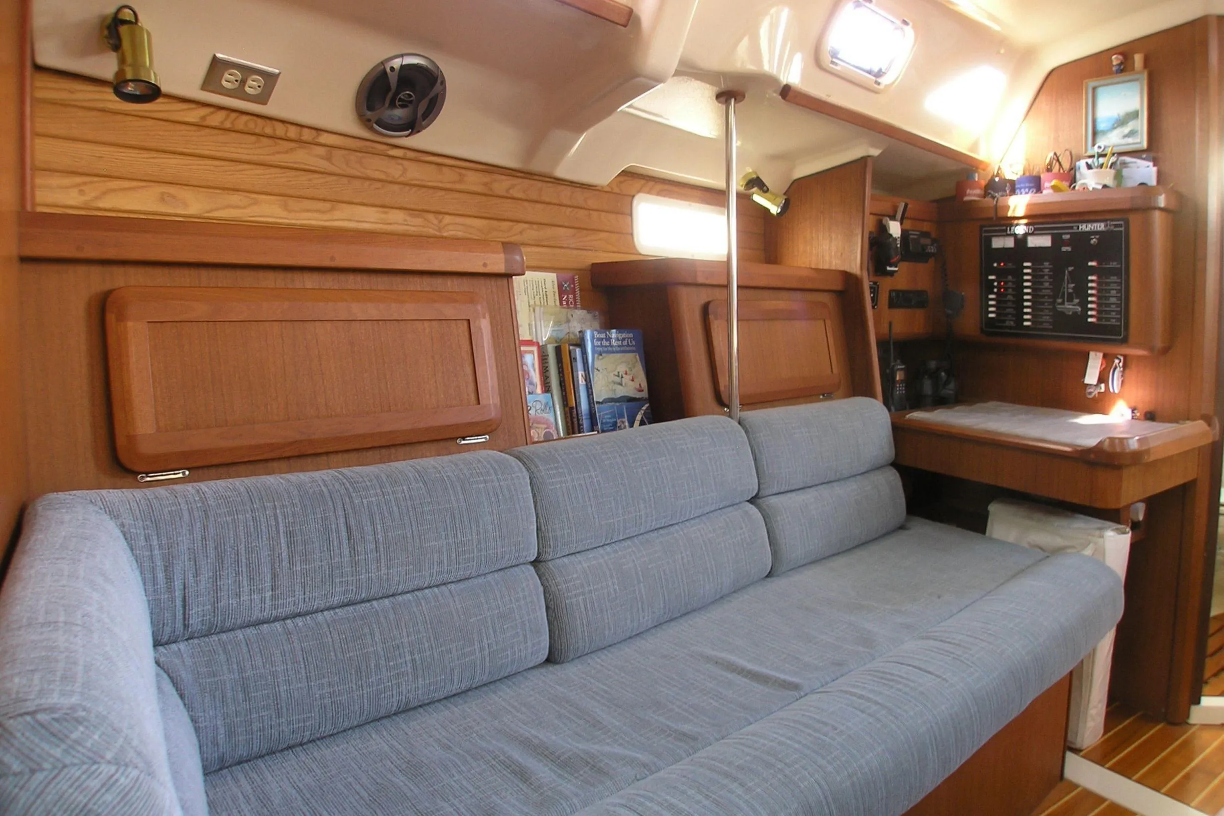 Interior of 1996 Hunter 37.5 Legend sailboat with blue sofa and navigation station.