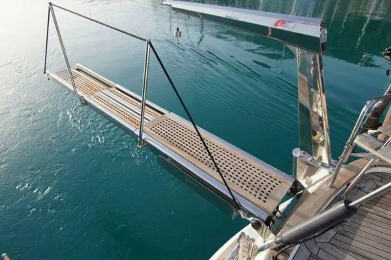 Persistence Yacht Photos Pics Gangway of a 2002 Hallberg-Rassy 53 yacht extending over clear blue water.