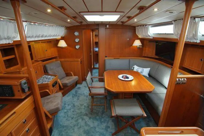 Persistence Yacht Photos Pics Interior of 2002 Hallberg-Rassy 53 yacht with wooden furnishings and cozy seating area.