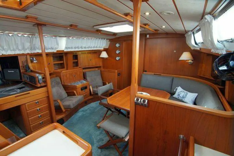 Persistence Yacht Photos Pics Interior of 2002 Hallberg-Rassy 53 yacht, featuring wooden furnishings and cozy seating area.