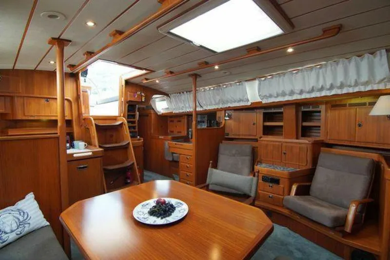Persistence Yacht Photos Pics Interior of a 2002 Hallberg-Rassy 53 yacht with wooden furnishings and seating area.