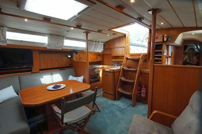 Persistence Yacht Photos Pics Interior of 2002 Hallberg-Rassy 53 yacht with cozy seating and wooden finishes.