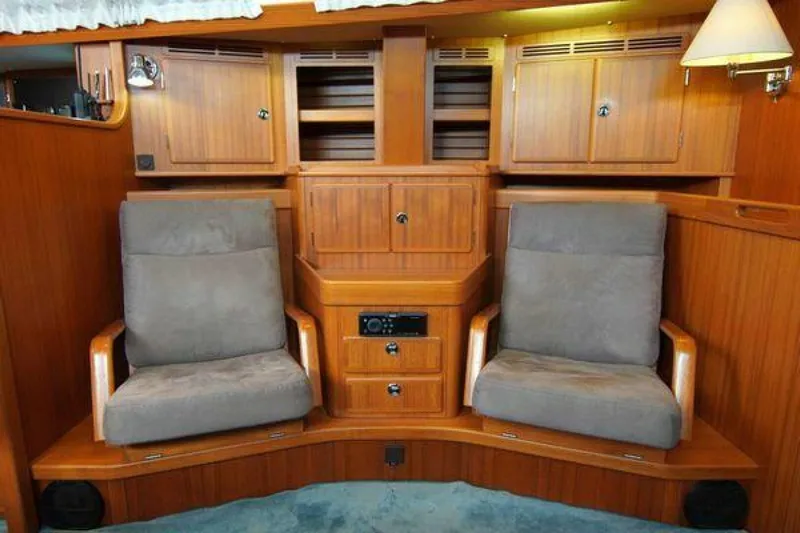 Persistence Yacht Photos Pics Interior of 2002 Hallberg-Rassy 53 yacht with wooden cabinetry and two cushioned chairs.