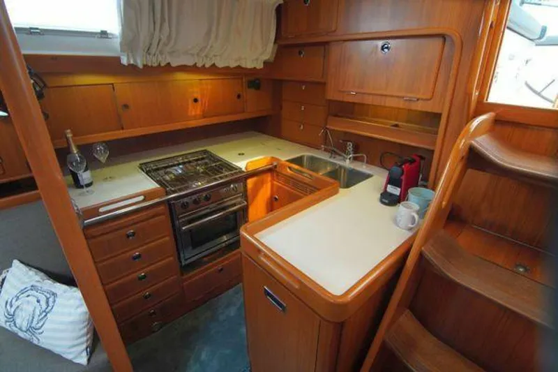 Persistence Yacht Photos Pics 2002 Hallberg-Rassy 53 yacht kitchen with wooden cabinetry, stove, sink, and stairs.
