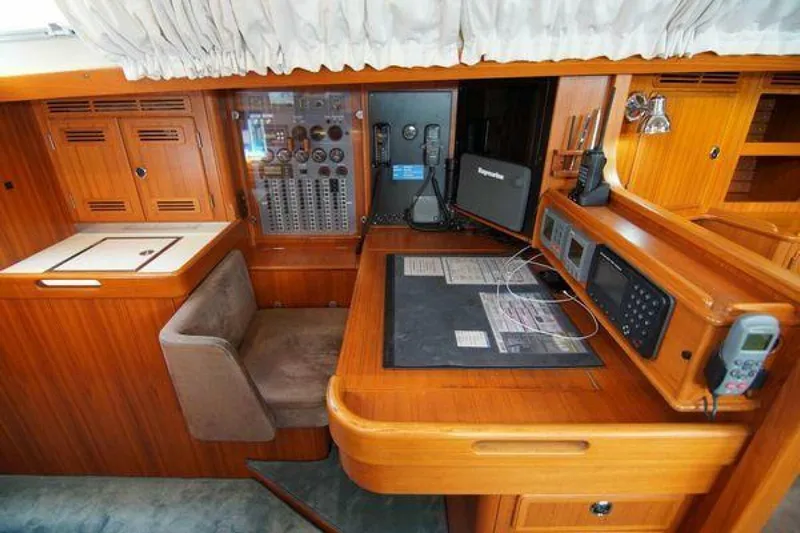 Persistence Yacht Photos Pics Navigation station of a 2002 Hallberg-Rassy 53 yacht with control panels and seating.