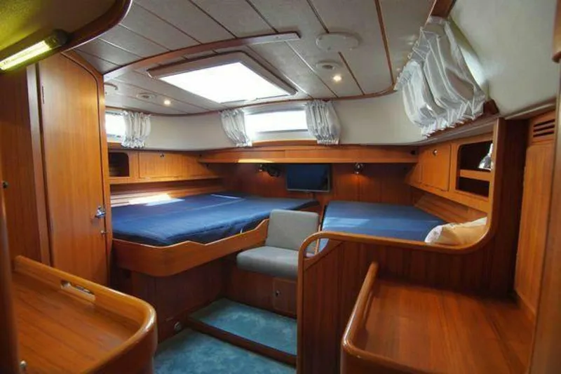 Persistence Yacht Photos Pics Luxurious interior of 2002 Hallberg-Rassy 53 yacht with wooden finish and blue bedding.