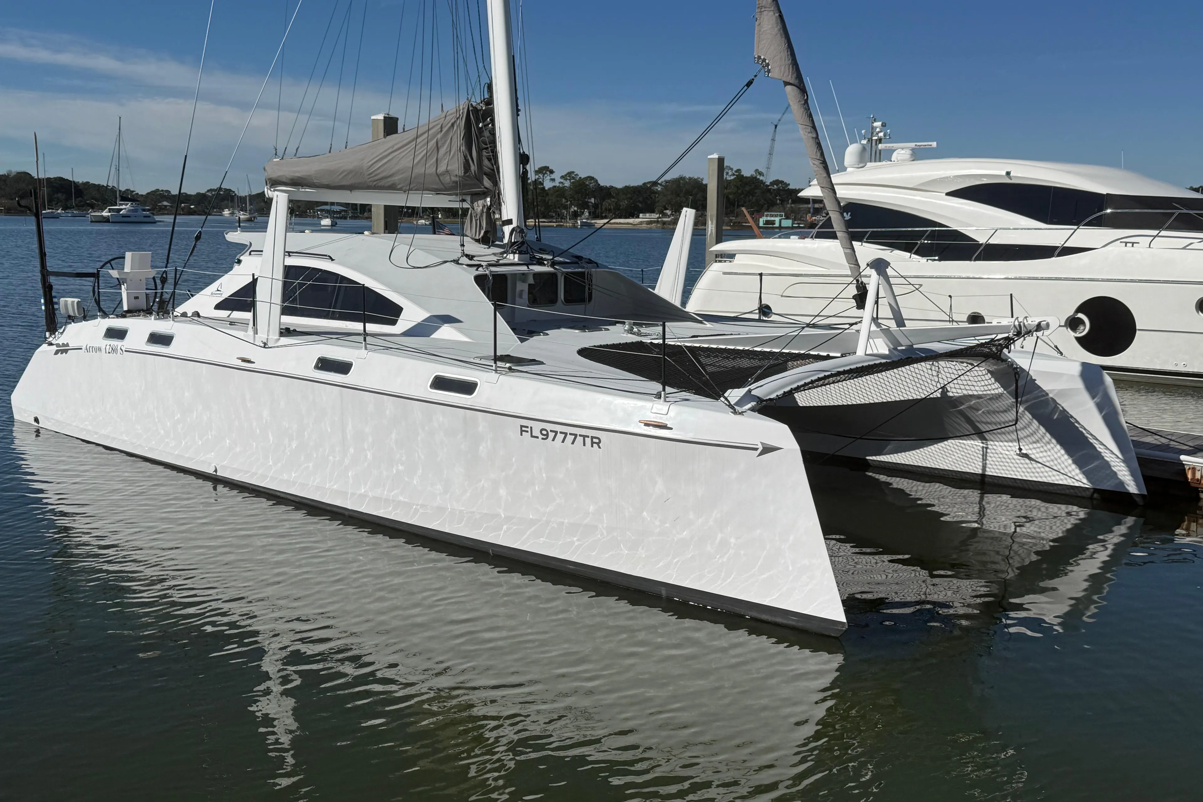 2023 Schionning 1850 S catamaran docked in a marina, reflecting on calm water.
