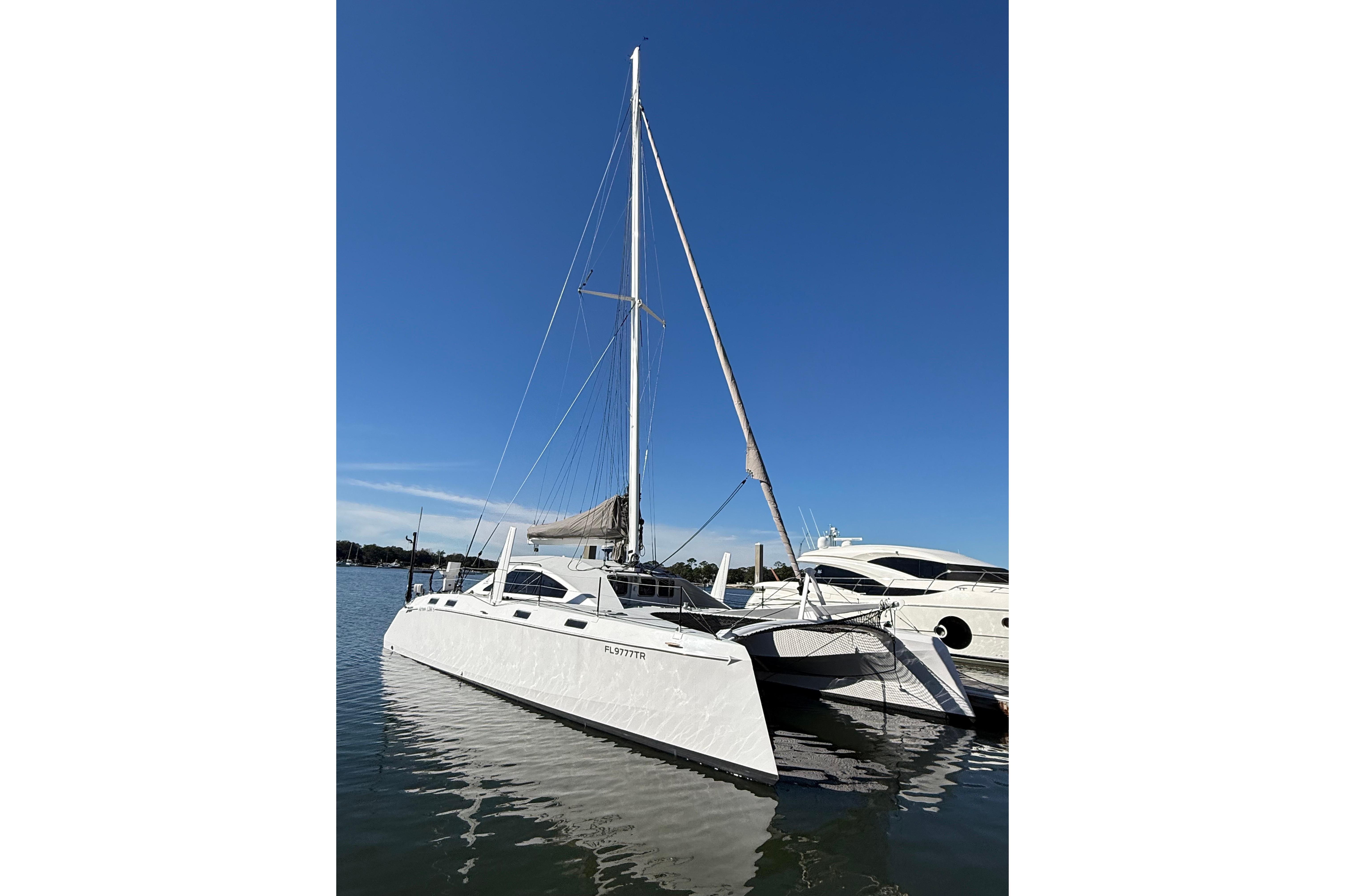 2023 Schionning 1850 S catamaran docked on calm water under clear blue sky.
