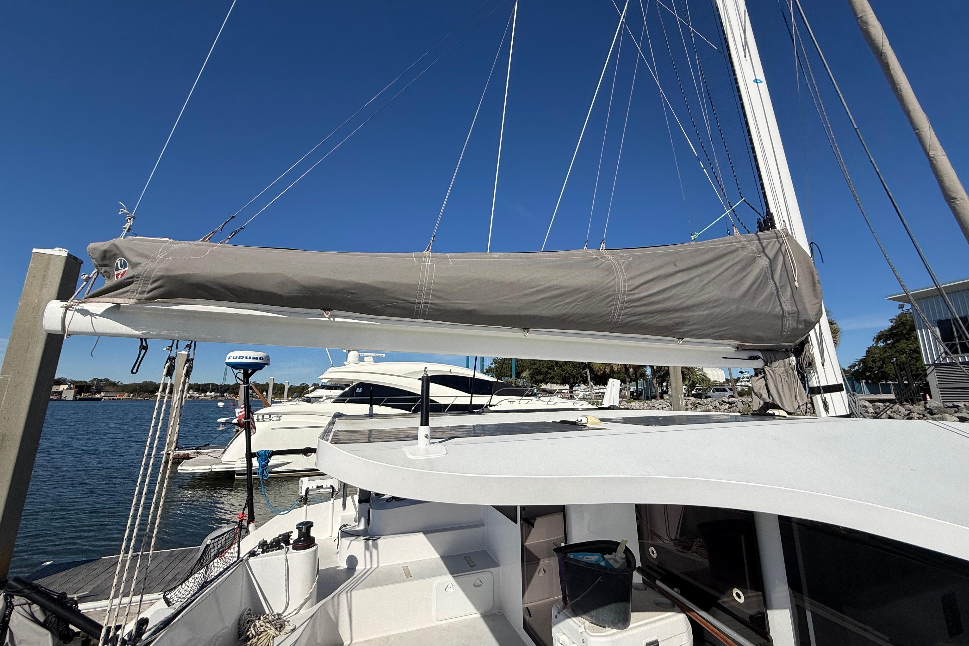 2023 Schionning 1850 S catamaran docked, featuring covered sail and clear blue sky.
