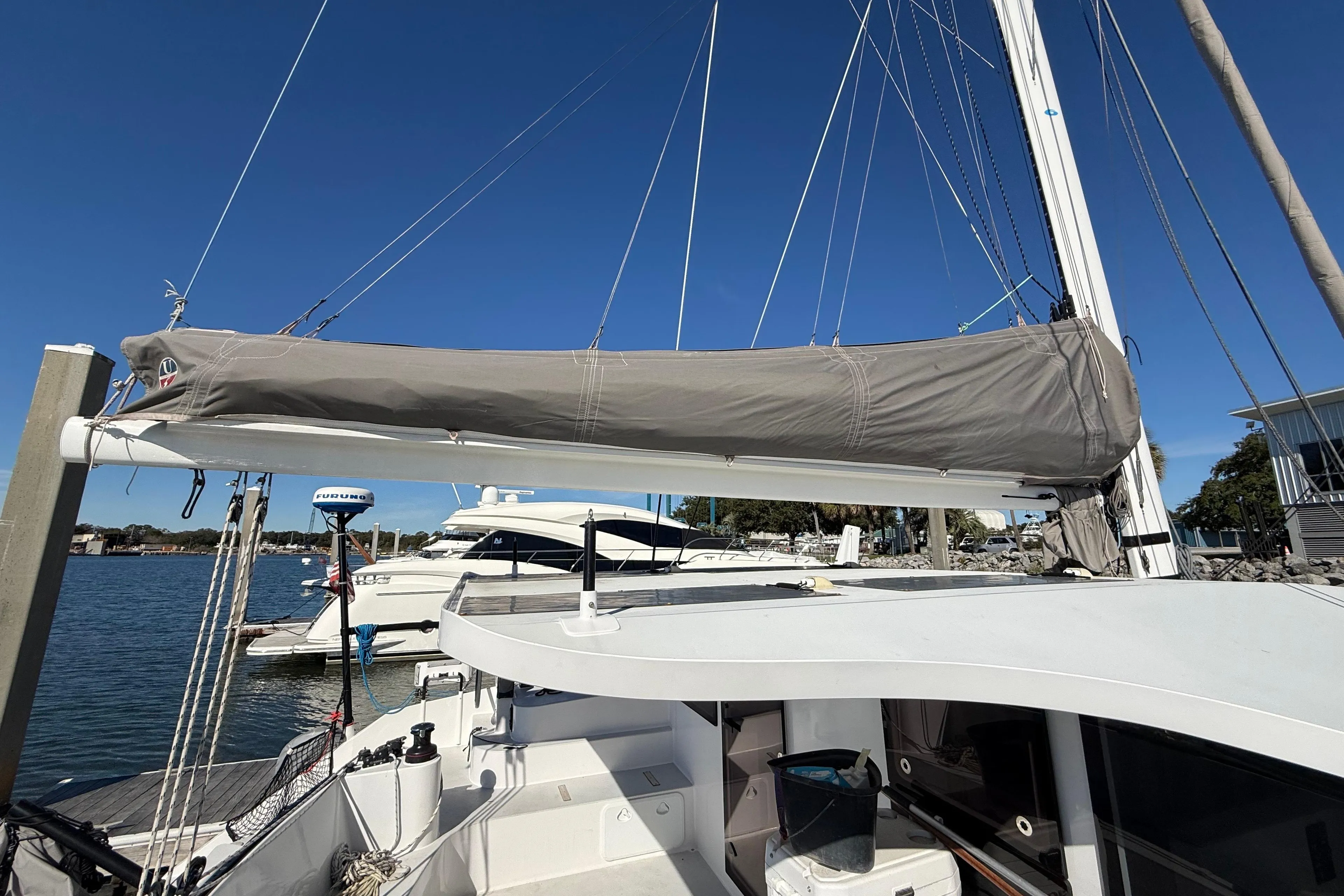 2023 Schionning 1850 S catamaran docked, featuring covered sail and clear blue sky.