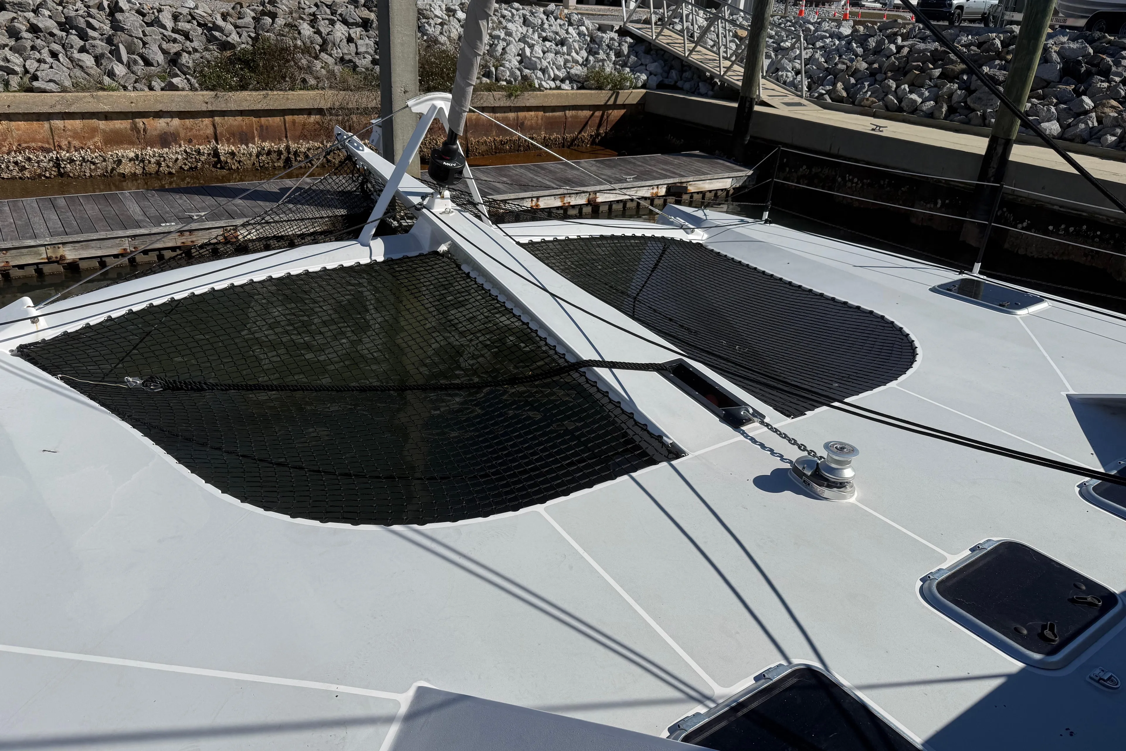 2023 Schionning 1850 S catamaran deck with netting, docked at a marina.