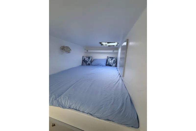  Yacht Photos Pics Cozy cabin interior of 2023 Schionning 1850 S with blue bedding and small window.