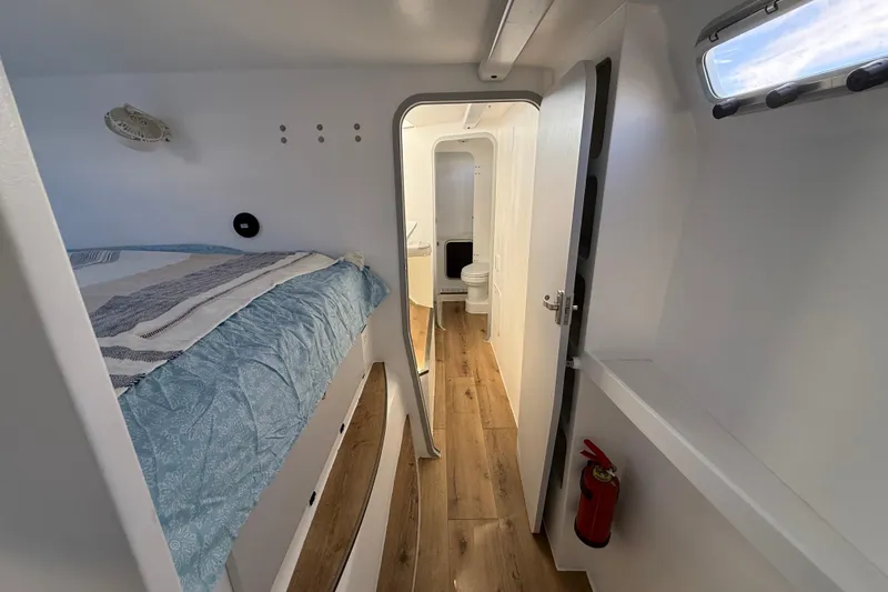  Yacht Photos Pics 2023 Schionning 1850 S interior with bed, wooden floor, and bathroom.