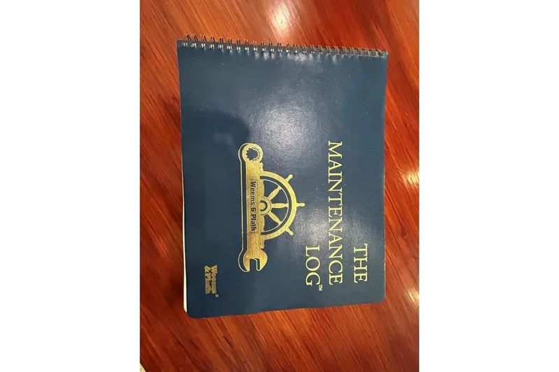 Island Hopper Yacht Photos Pics Blue maintenance logbook for Crosswater Passagemaker 49, 2001 model, on wooden surface.