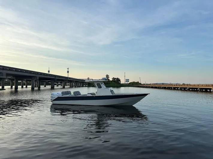  Yacht Photos Pics Custom 2003 Leblanc CC boat on calm water near a bridge at sunset.
