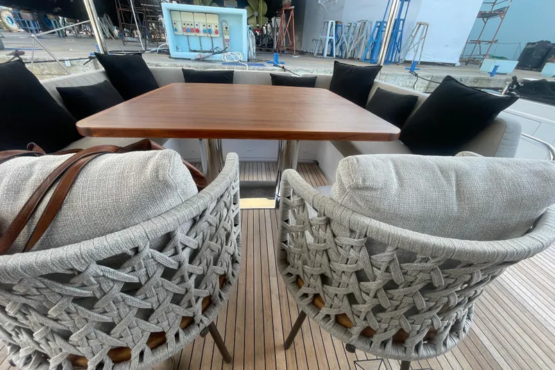Azimut 66 Magellano Yacht Photos Pics Luxury seating area on Azimut Magellano 66 yacht, featuring woven chairs and wooden table, 2024 model.