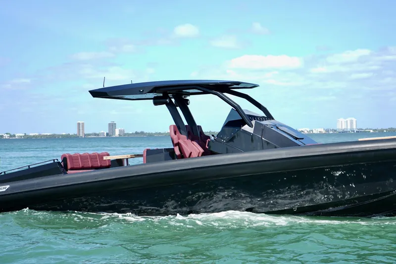  Yacht Photos Pics 2024 Skipper 42 boat cruising on clear blue water with city skyline in background.
